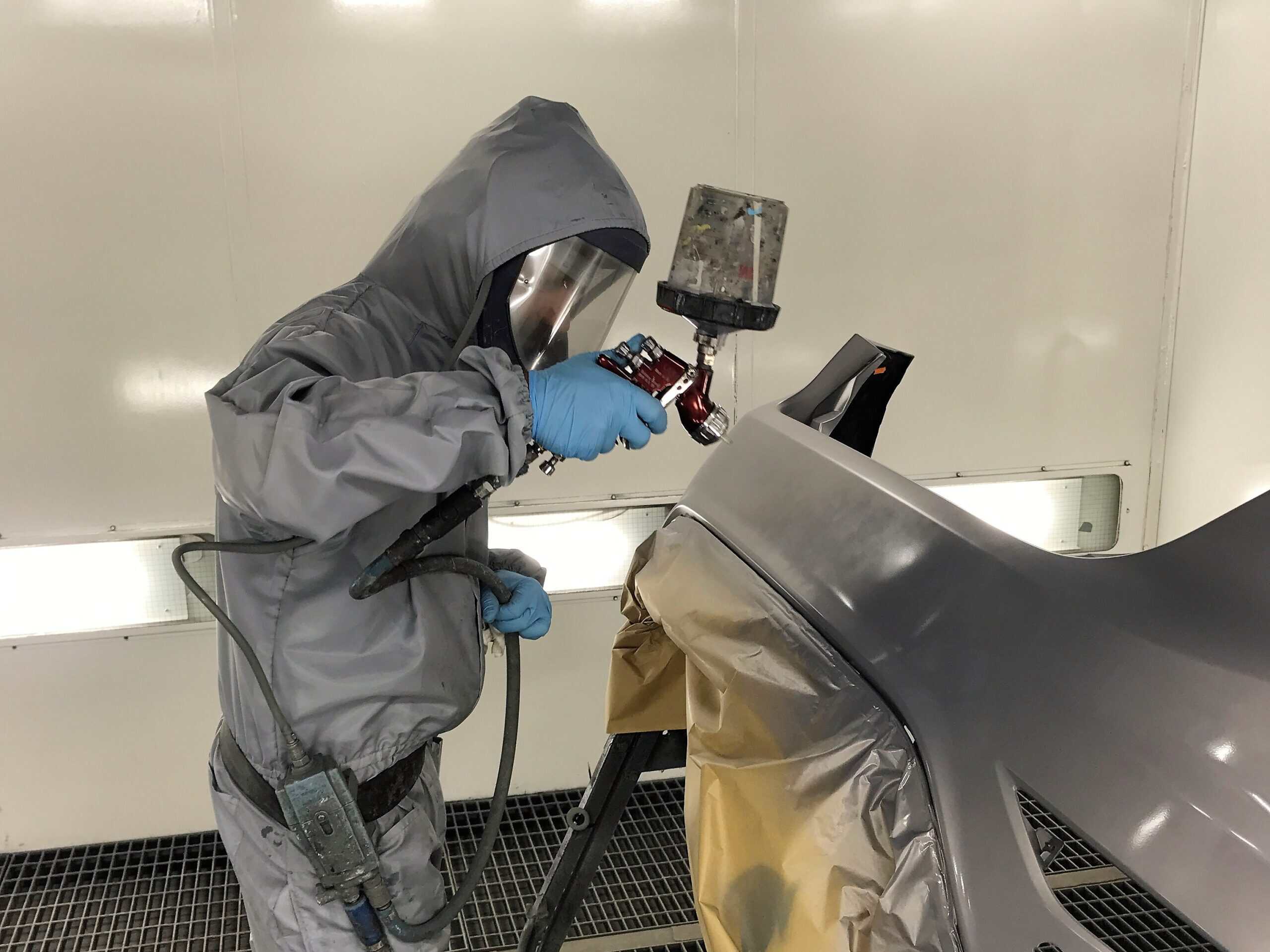 Automotive repair technician inspecting a car for collision damage.
